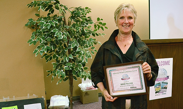 A pretty woman in her 60s holding an award. 