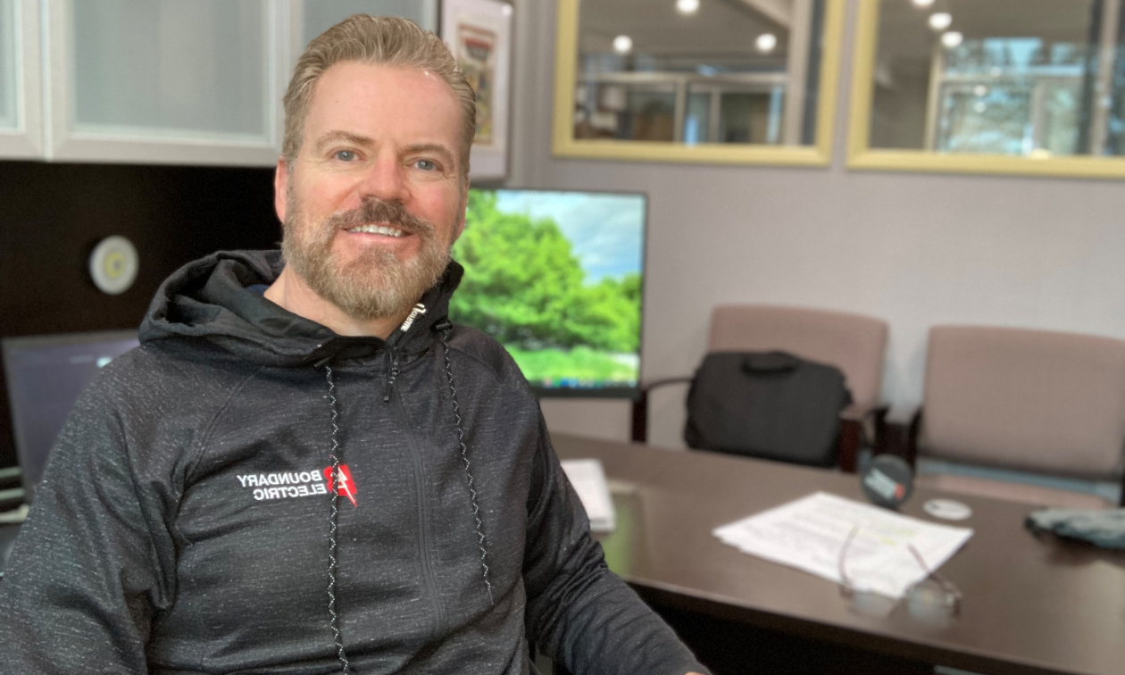 Mike Freed smiles as he sits next to his computer in his office. 