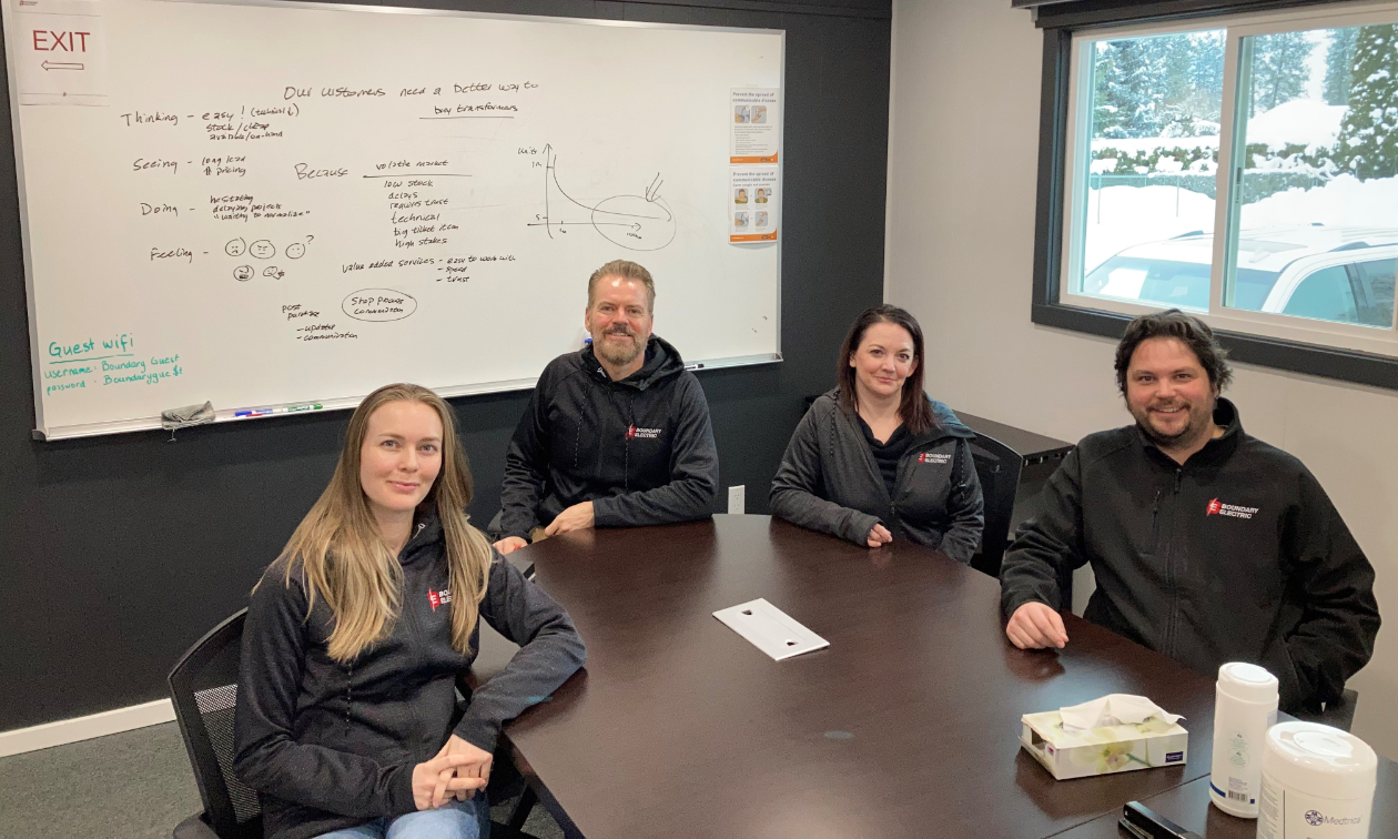 Four Boundary Electric employees sit around a table in a boardroom. 