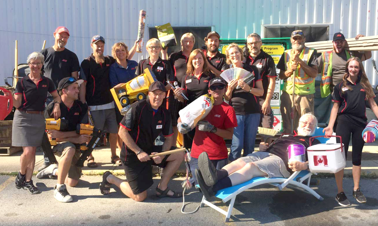 Jeff Davie (up front in the middle with a black hat), his wife, Monica Davie (behind Jeff, wearing a blue shirt), and the team at Kaslo Building Supplies pose for a group photo. 