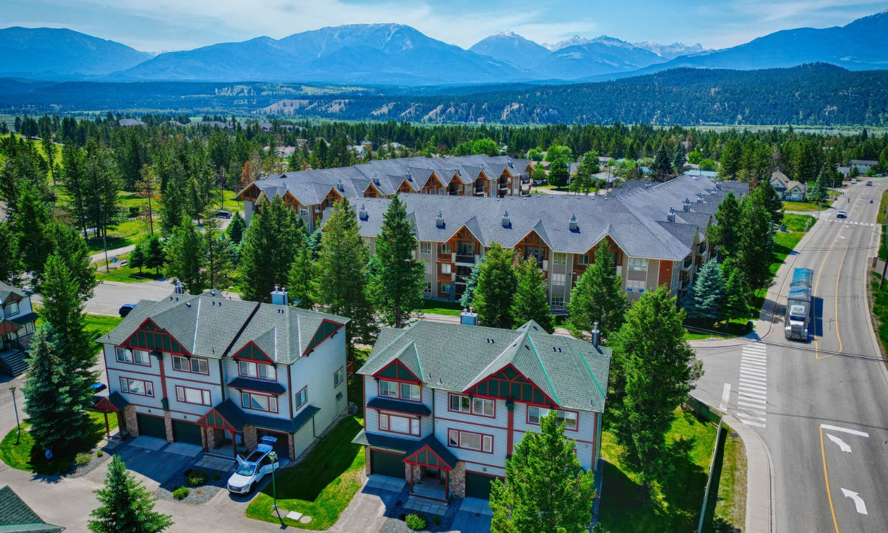 An aerial view of the Columbia Valley showcases some pristine, tall homes among trees and distant mountains. 