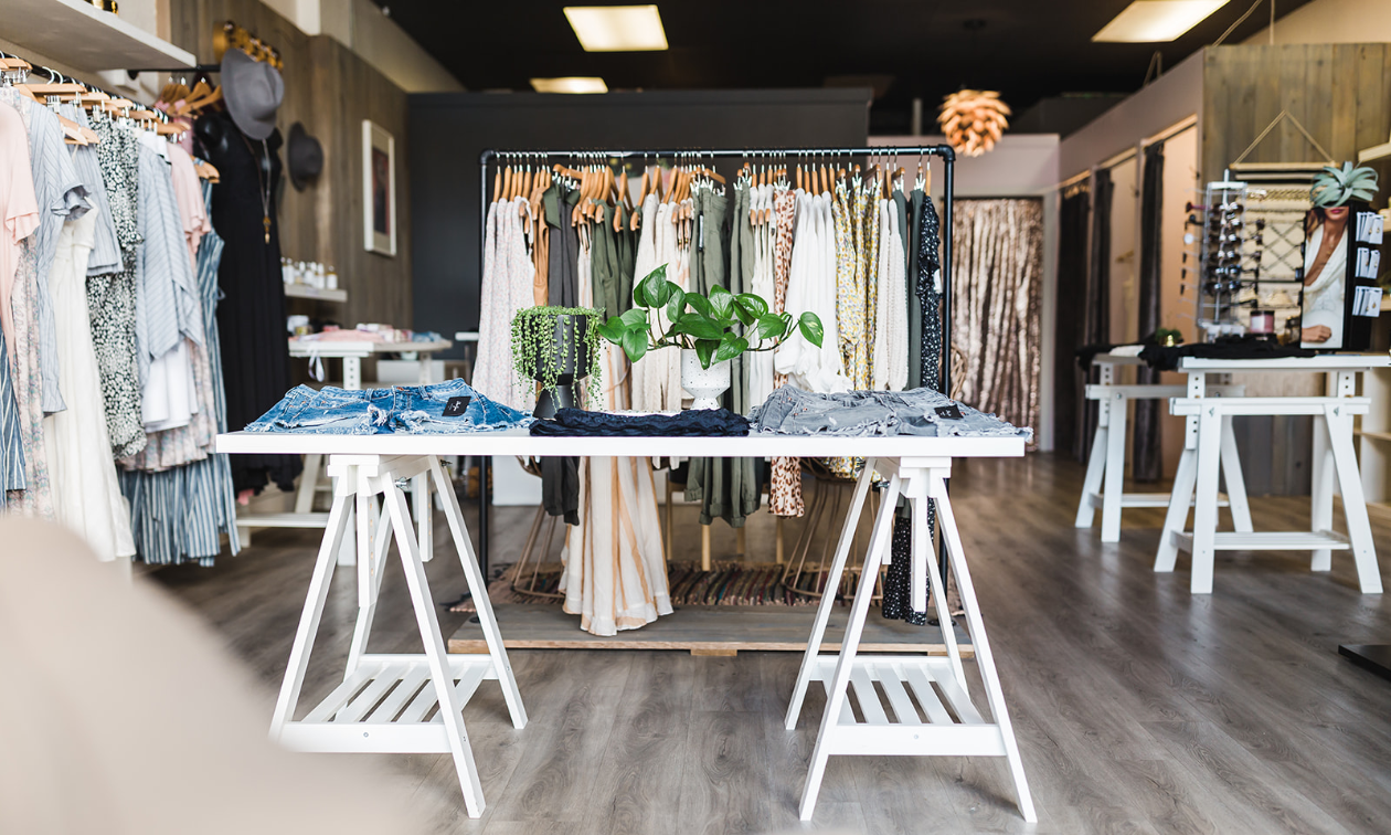 A white wooden table displays various articles of clothing.