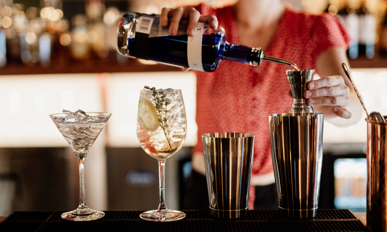 A bartender pours alcoholic drinks at a pristine bar. 