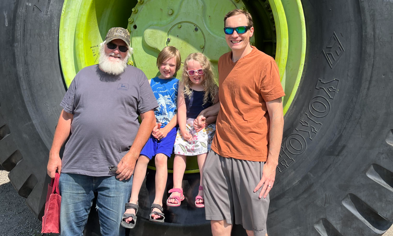 John, Gus, Annabelle, and Kyle Born lean against one of the Terex Titan’s big green wheels. 