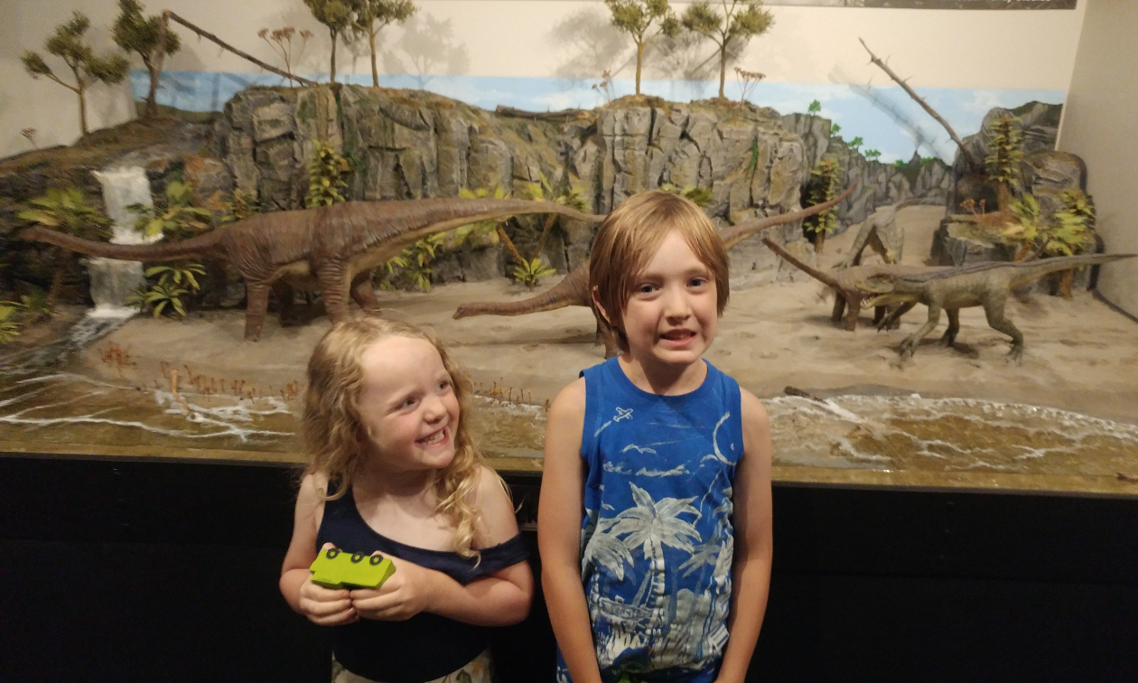 Annabelle and Gus Born smile in front of a dino diorama inside the Sparwood Museum. 