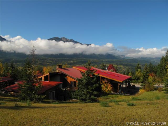 Family-style European inn with cloud-covered mountains in the background and blue sky above