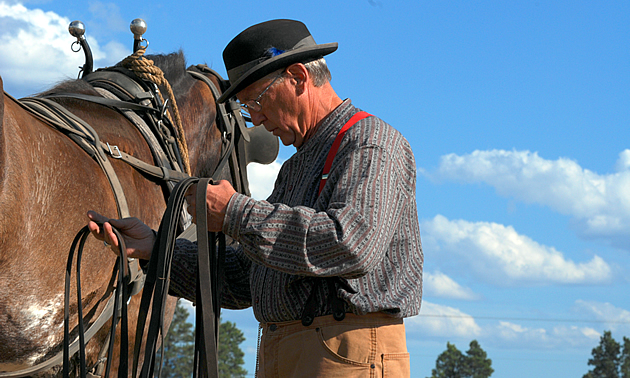 A man stands in heritage clothing by his horse at Fort Steele