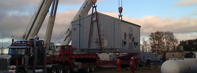 Loading a large container by crane onto a flatbed truck. 