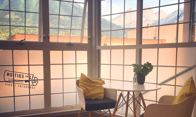 Interior of 2nd Edition Coworking in Fernie, showing comfy set of chairs, small table and windows with mountain view outside. 