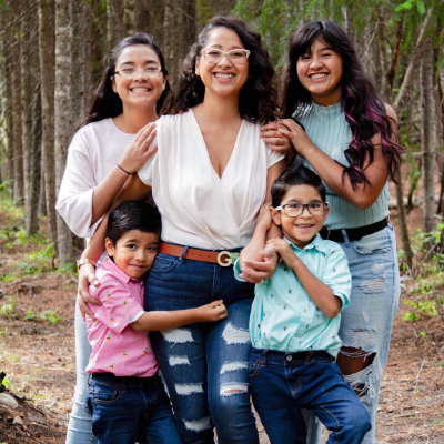 Luz Hernandez and her four children smile while hugging each other.