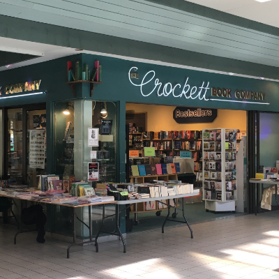 The Crockett Book Co. is a bookstore with a couple of display tables and stands in front of the store.