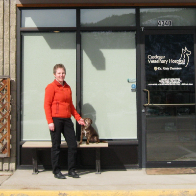 Dr. Kristy Dennison stands in front of Castlegar Veterinary Hospital with a dog.