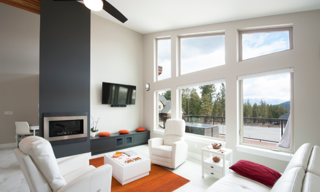 A mostly white, modern living room with large windows.