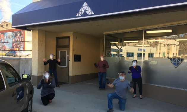 Five workers pose with face shields outside of Austin Innovation.