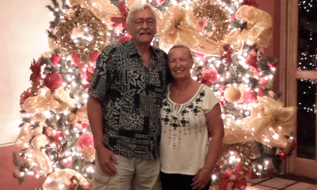 Gladys and Brian Goss-Laing smile in front of a Christmas tree.