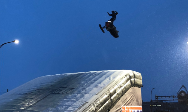 A snowmobiler gets major air before landing on a ramp.