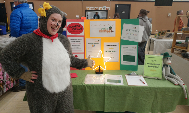 Lisa Aasebo-Kennedy is dressed up like a squirrel in front of an informational stand at a farmers market in Cranbrook.