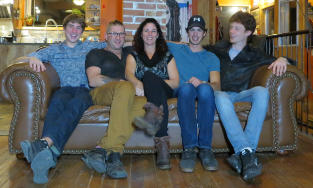 Trey, Gentry, Jacquelyn, Noah and Padn Konkin sit on a couch in a wooden home.