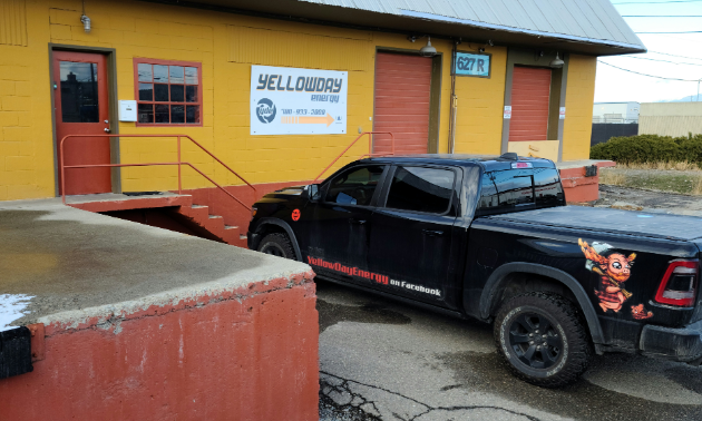 Yellowday Energy is a yellow building with an orange door. A black pickup truck with Yellowday Energy written on the side is parked in front.