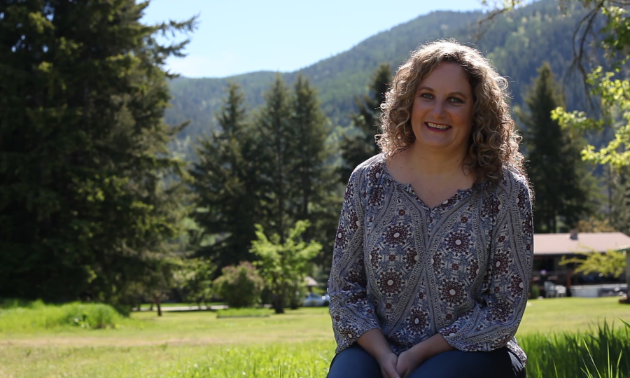 Leeza Zurwick smiles in a green farm setting amidst trees.