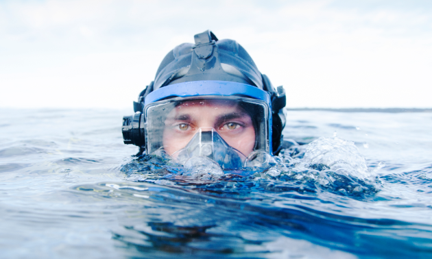 Mike Irvine scuba dives with the top of his head above the water.