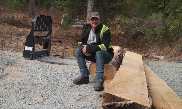 Darrin Brown sits on some cut up logs