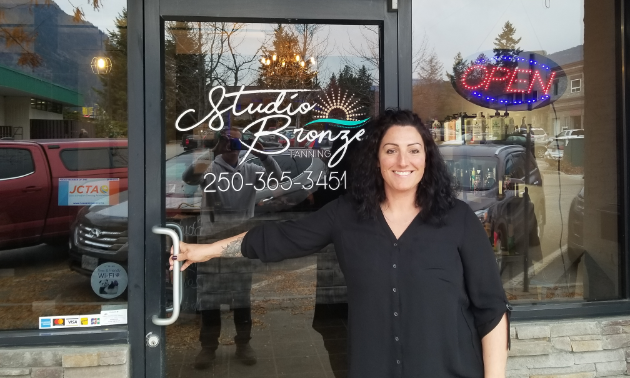 Nikki Luxton smiles while holding the handle of the door to enter Studio Bronze.