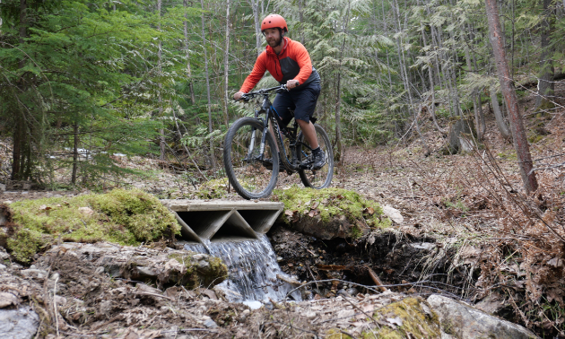 Jonathan Ladouceur, head of engineering, tests his printed bridge on one of the Kootenay Lake Village mountain bike trails.