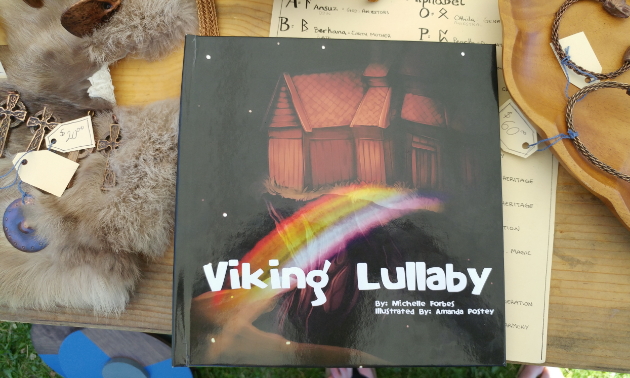 The cover of Viking Lullaby shows a wooden home with a rainbow bridge leading up to it