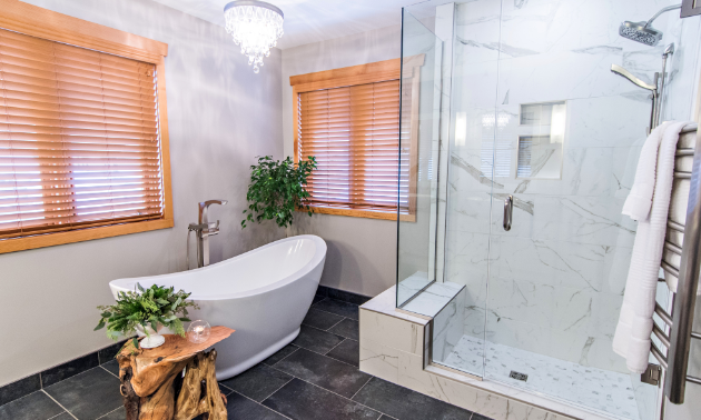 A bright white bathroom with an egg-shaped bathtub and square transparent shower. 