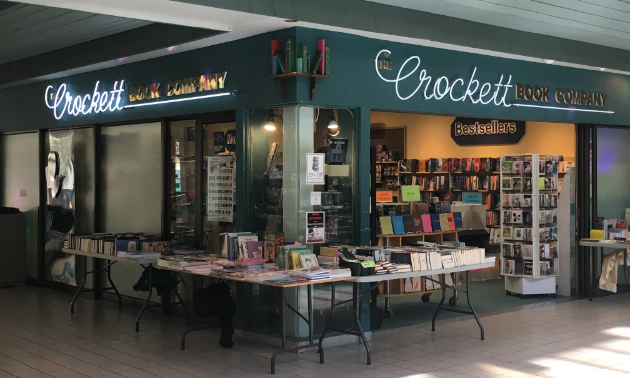 The Crockett Book Co. is a bookstore with a couple of display tables and stands in front of the store.