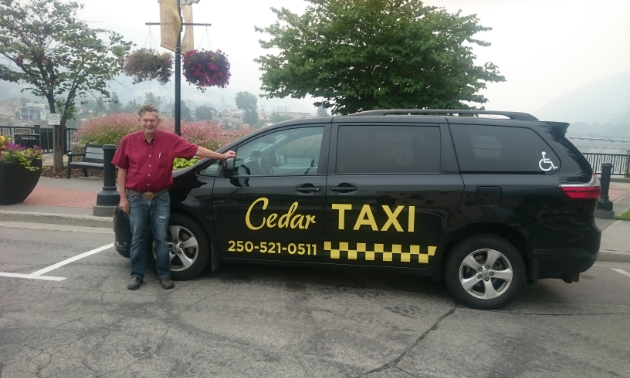 Ian Thomas stands next to his Cedar Taxi van