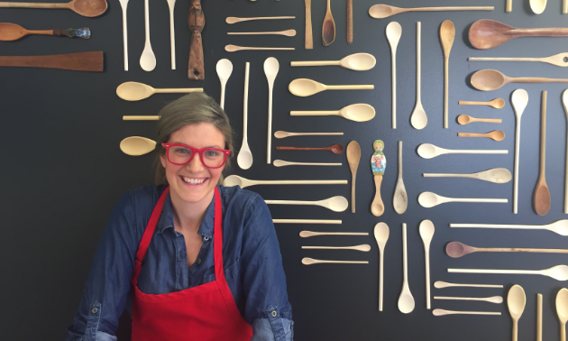 Kayla Sebastian stands in front of a wall of wooden spoons