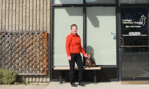 Dr. Kristy Dennison stands in front of Castlegar Veterinary Hospital with a dog.