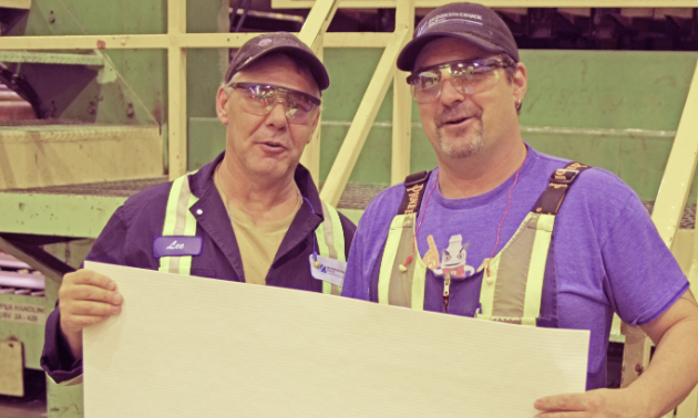 (L to R) Lee Spence and Wilf Davis, employees of Skookumchuck Pulp Inc., hold a sheet of high-quality Northern Bleached Softwood Kraft (NBSK) pulp. These sheets of pulp, measuring 86 centimetres by 74 centimetres, are stacked together to produce bales of pulp. Each bale weighs approximately 245 kilograms.