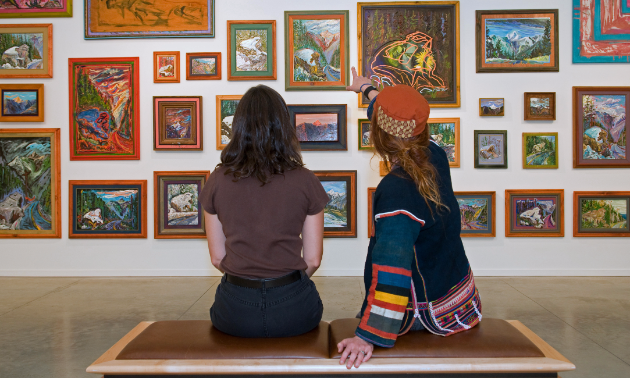 Picture of two people looking at paintings in an art gallery. 