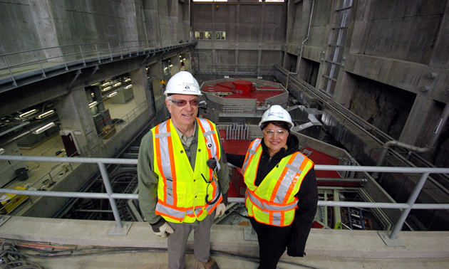 An older gentleman and a women standing above the turbines inside Waneta. 