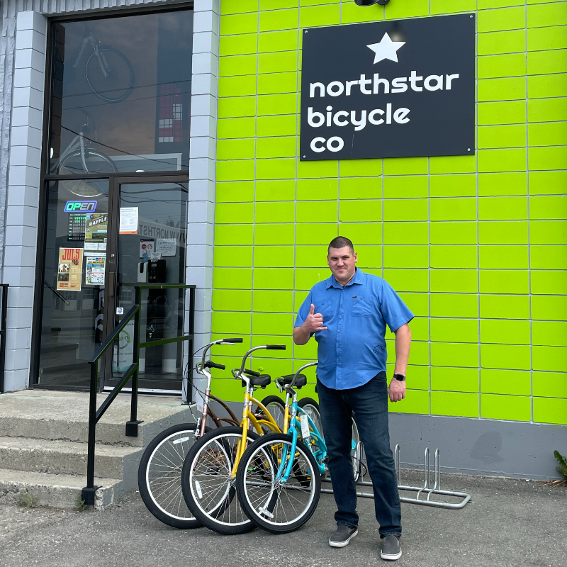 Jared Williams stands in front of Northstar Bicycle Co., a lime green building in Cranbrook, B.C.