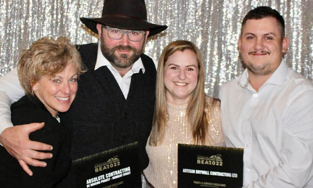 Owners of Absolute Contracting and Artisan Drywall, holding awards. 