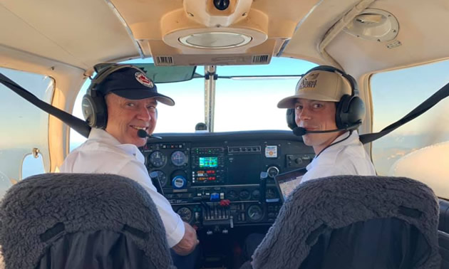 Two pilots in cockpit of small plane. 