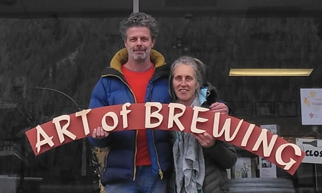 Owners Breg and Maarten Lammers are holding a sign that says Art of Brewing, the name of their store.