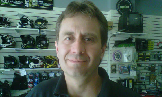 Head shot of 40-ish man with wall display of mechanical components in the background.