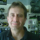 Head shot of 40-ish man with wall display of mechanical components in the background.