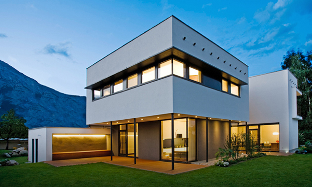 A graphic passive solar home rises attractively into the sky. It is white and features walls of windows.