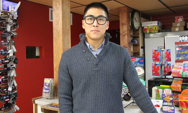 Young Asian man in large black-framed glasses smiles at the camera