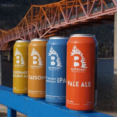 Row of cans sitting on ledge, Nelson's iconic orange bridge in background. 