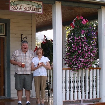 Jo Anne and Patrick Burke standing on the veranda of their Bed and Breakfast, the Old Nurses Residence, in Fernie B.C.