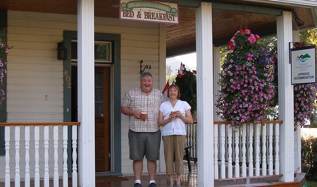 Jo Anne and Patrick Burke standing on the veranda of their Bed and Breakfast, the Old Nurses Residence, in Fernie B.C.