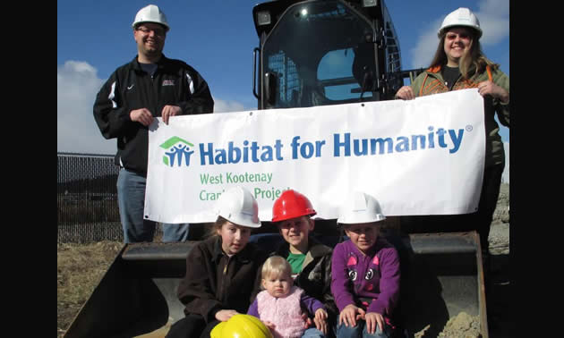 Parents David and Coreena Berry hold the Habitat for Humanity banner while children (left to right) Hanna, 11, Jordan, 8, Alysha, 10, and Samantha, 16 months, show off their hardhats.