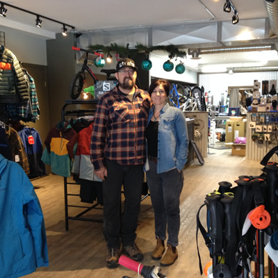 Angela and Perry Symes stand in their shop surrounded by gear. 